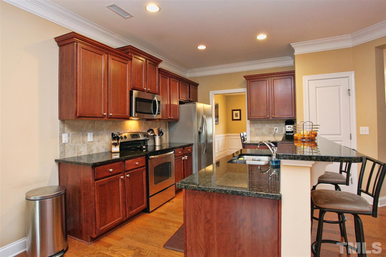 618 Democracy Street Raleigh, NC 27603 - Photo 8 of 24 a kitchen with granite countertop wooden cabinets a stove top oven a sink and dishwasher