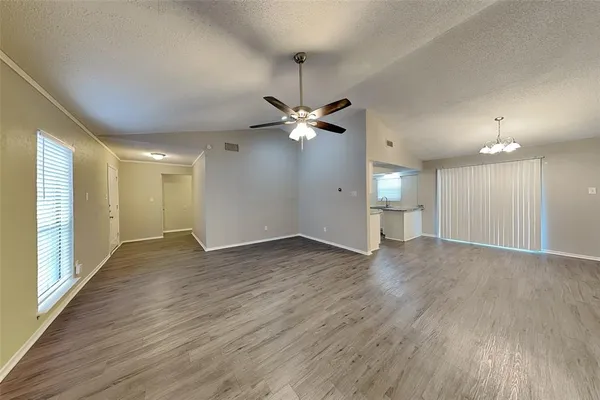 a view of an empty room and wooden floor and a ceiling fan