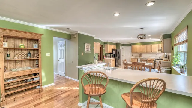 a kitchen with stainless steel appliances granite countertop a stove a sink a dining table and chairs