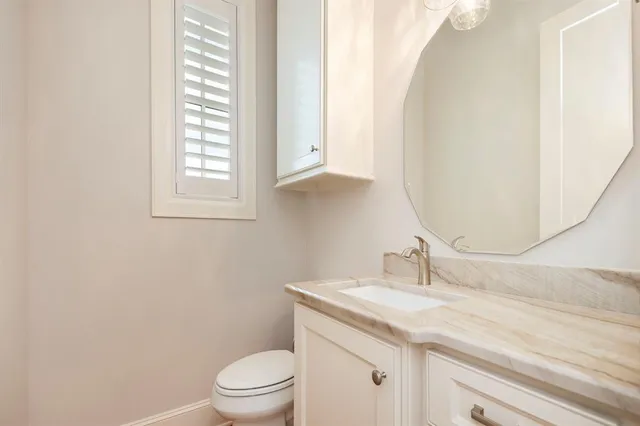 a bathroom with a granite countertop sink toilet and mirror