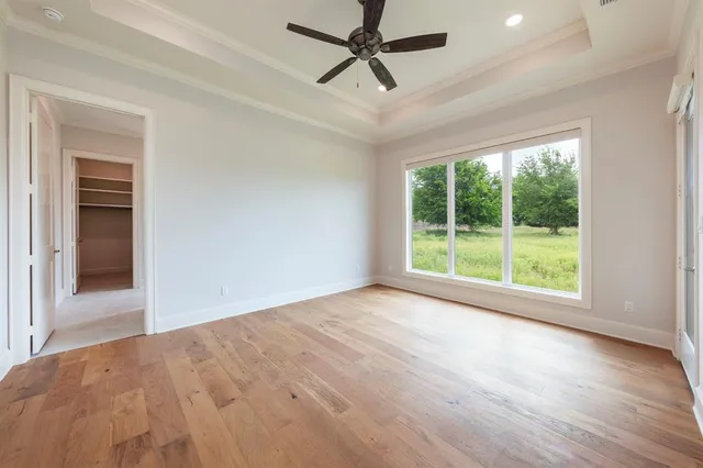 a view of empty room with wooden floor and fan