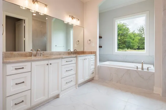 a bathroom with a granite countertop bathtub sink vanity and mirror
