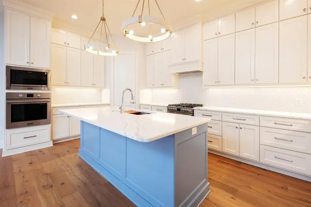 a kitchen with kitchen island granite countertop a sink a counter space appliances and cabinets