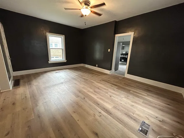 a view of empty room with wooden floor and fan