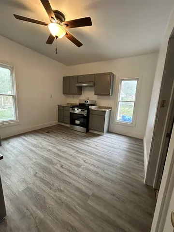 a view of empty room with wooden floor and fan