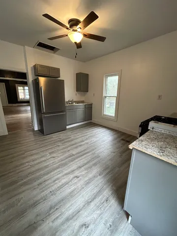 a kitchen with stainless steel appliances granite countertop a sink a microwave oven a refrigerator with island and wooden floor