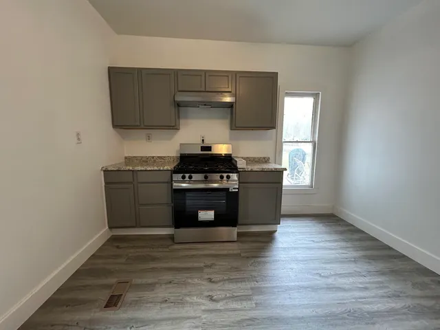 a kitchen with stainless steel appliances a stove and white cabinets