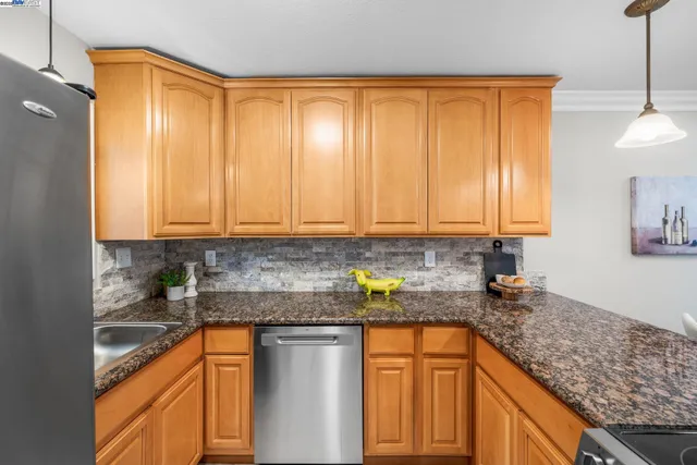 a kitchen with stainless steel appliances granite countertop wooden cabinets a sink and dishwasher a stove with wooden floor