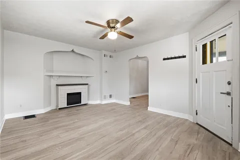 a view of an empty room with wooden floor fireplace and a window