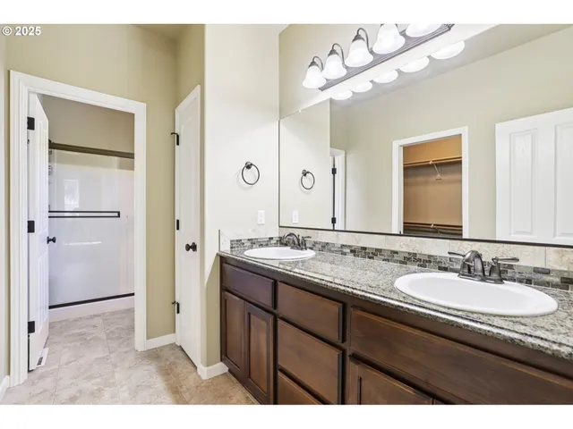 a bathroom with a granite countertop sink a large mirror and a shower