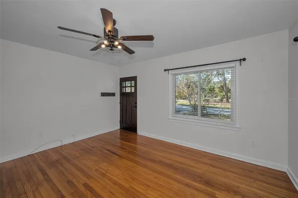 a view of an empty room with wooden floor and a window