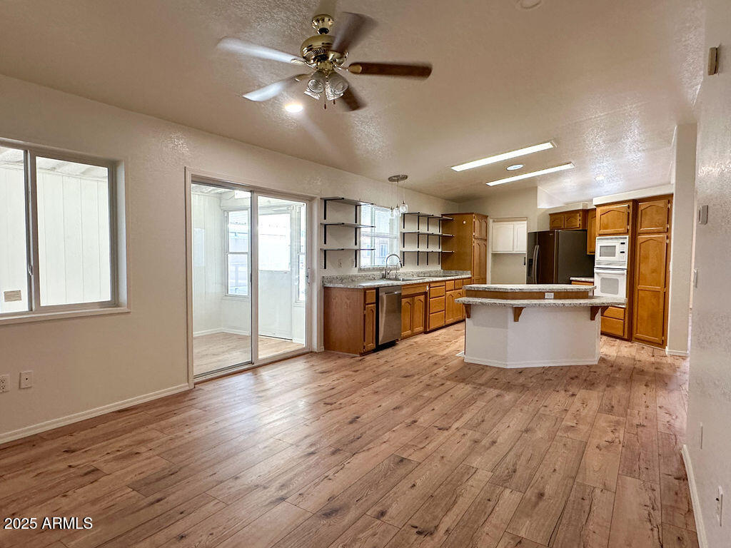 2054 North Thornton Road, Unit 187 Casa Grande, AZ 85122 - Photo 10 of 14 a large kitchen with stainless steel appliances kitchen island a large counter top and wooden floors