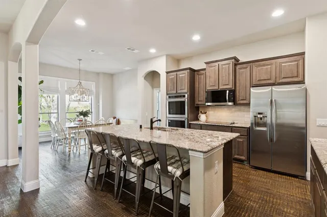 a kitchen with stainless steel appliances granite countertop a table chairs sink refrigerator and microwave