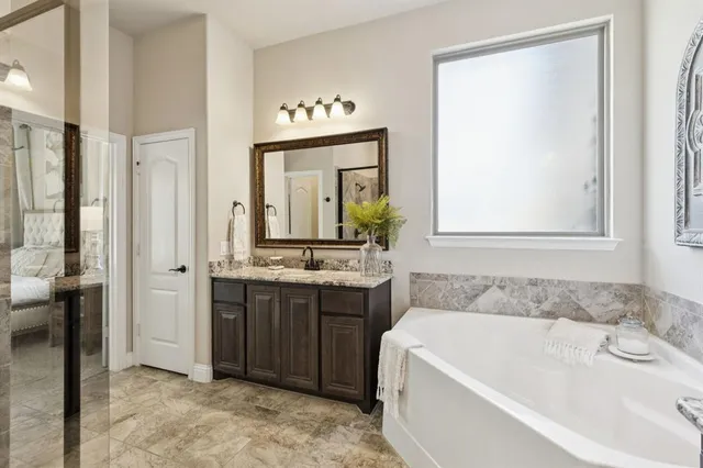 a spacious bathroom with a tub sink and mirror