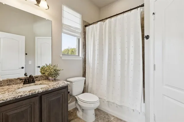 a bathroom with a granite countertop sink toilet and a mirror