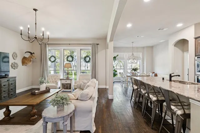 a view of a dining room and livingroom with furniture wooden floor a chandelier