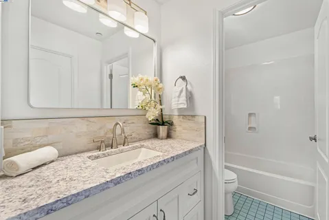 a bathroom with a granite countertop sink a toilet and bathtub