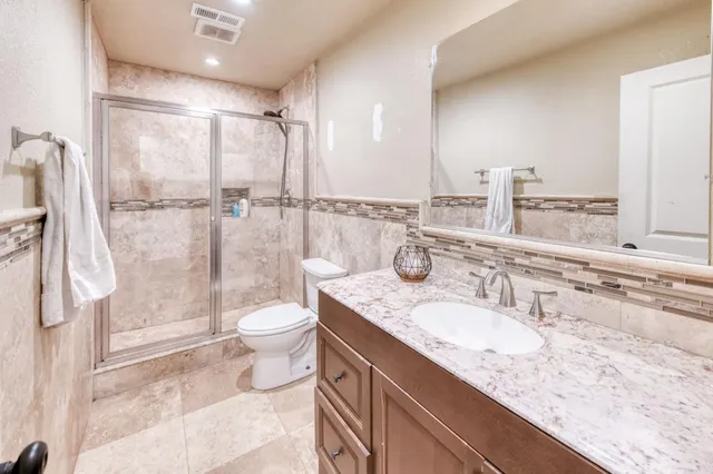 a bathroom with a granite countertop sink toilet and shower