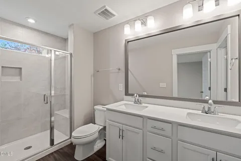 a bathroom with a double vanity sink toilet and shower