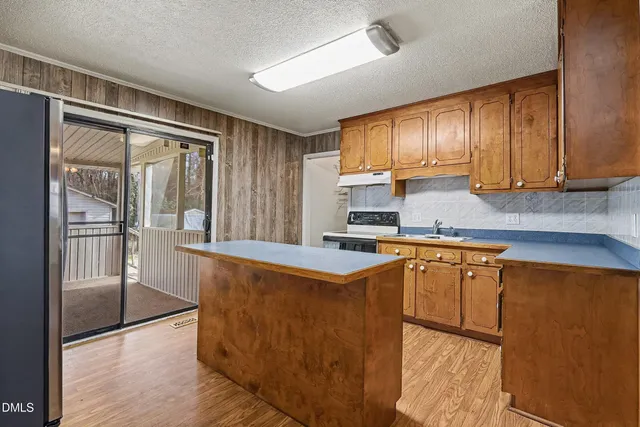 a kitchen with stainless steel appliances granite countertop a refrigerator a sink dishwasher a stove and white countertops with wooden floor