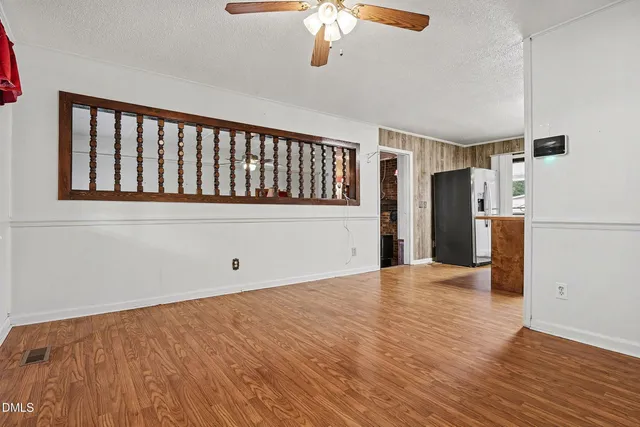 a view of empty room with wooden floor and fan