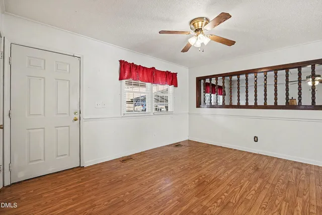 a view of a room with wooden floor and a ceiling fan