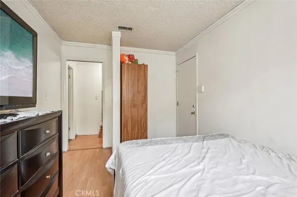 a bedroom with a bed and a flat tv screen on a dresser