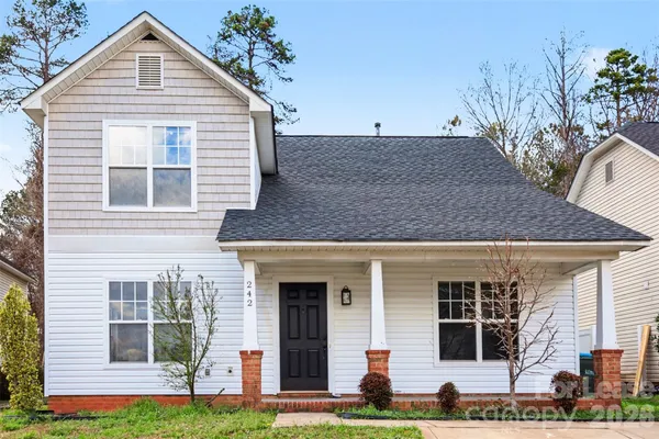 a front view of a house with a yard and potted plants
