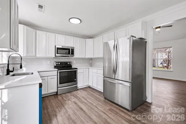 a kitchen with granite countertop stainless steel appliances a refrigerator a stove top oven a sink and cabinets