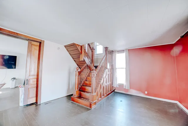 a view of an empty room with window and stairs