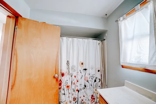 a bathroom with a shower curtain and a window