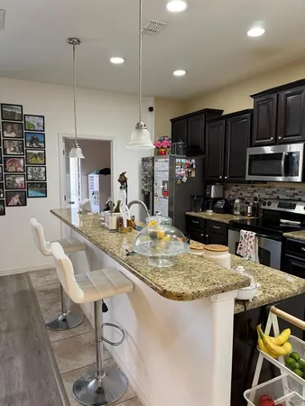 a kitchen with stainless steel appliances granite countertop a sink a stove a refrigerator and chairs