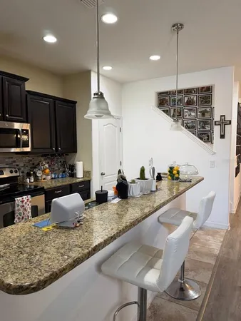 a large kitchen with granite countertop a sink a counter space appliances and cabinets
