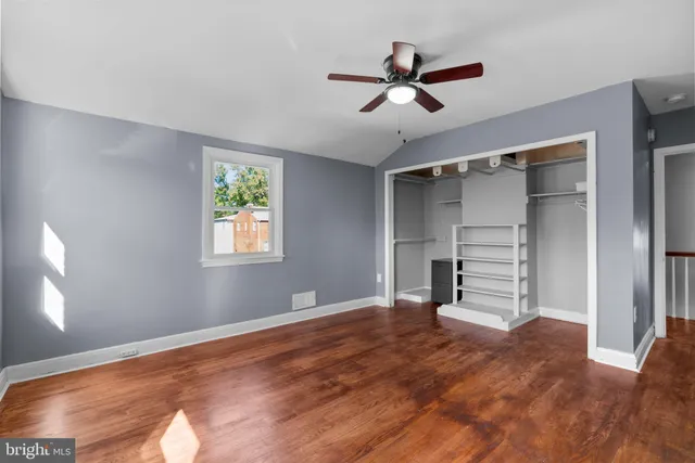 a view of empty room with wooden floor and fan