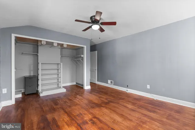 a view of an empty room with a ceiling fan and wooden floor