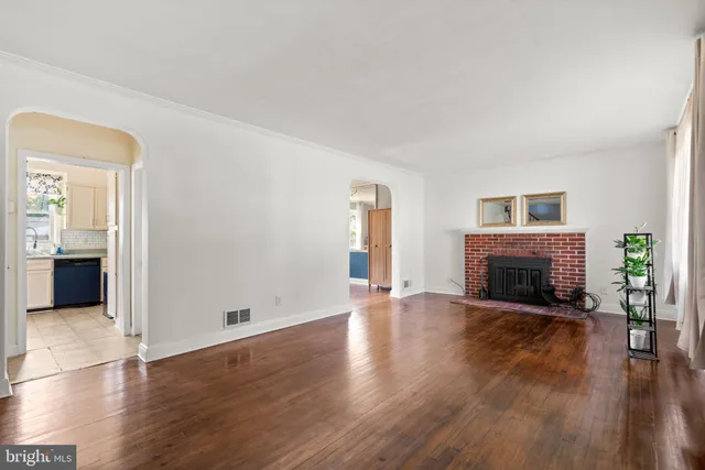 an empty room with wooden floor fireplace and windows