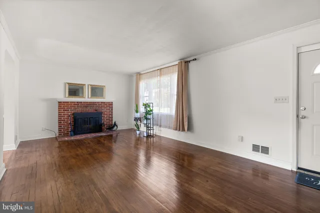 an empty room with wooden floor fireplace and windows