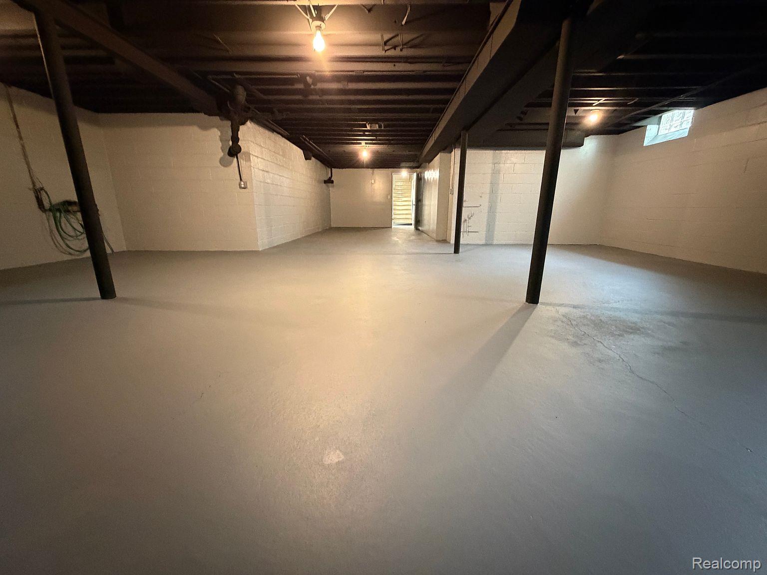 3520 Rayburn Road Bloomfield Hills, MI 48304 - Photo 21 of 26 Expansive unfinished basement featuring painted concrete flooring, white cinder block walls, exposed joists, and a partial staircase