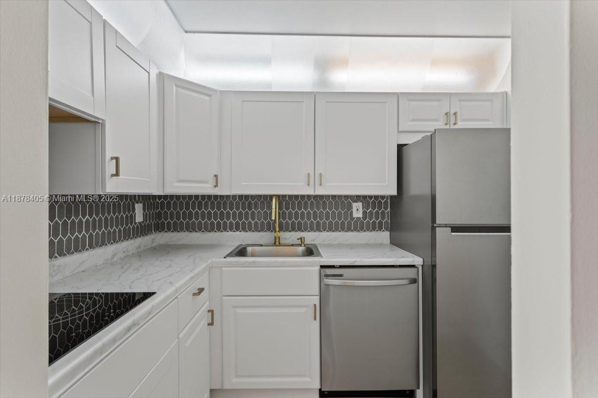 2899 Collins Avenue, Unit 1104 Miami Beach, FL 33140 - Photo 6 of 21 a kitchen with a refrigerator and cabinets