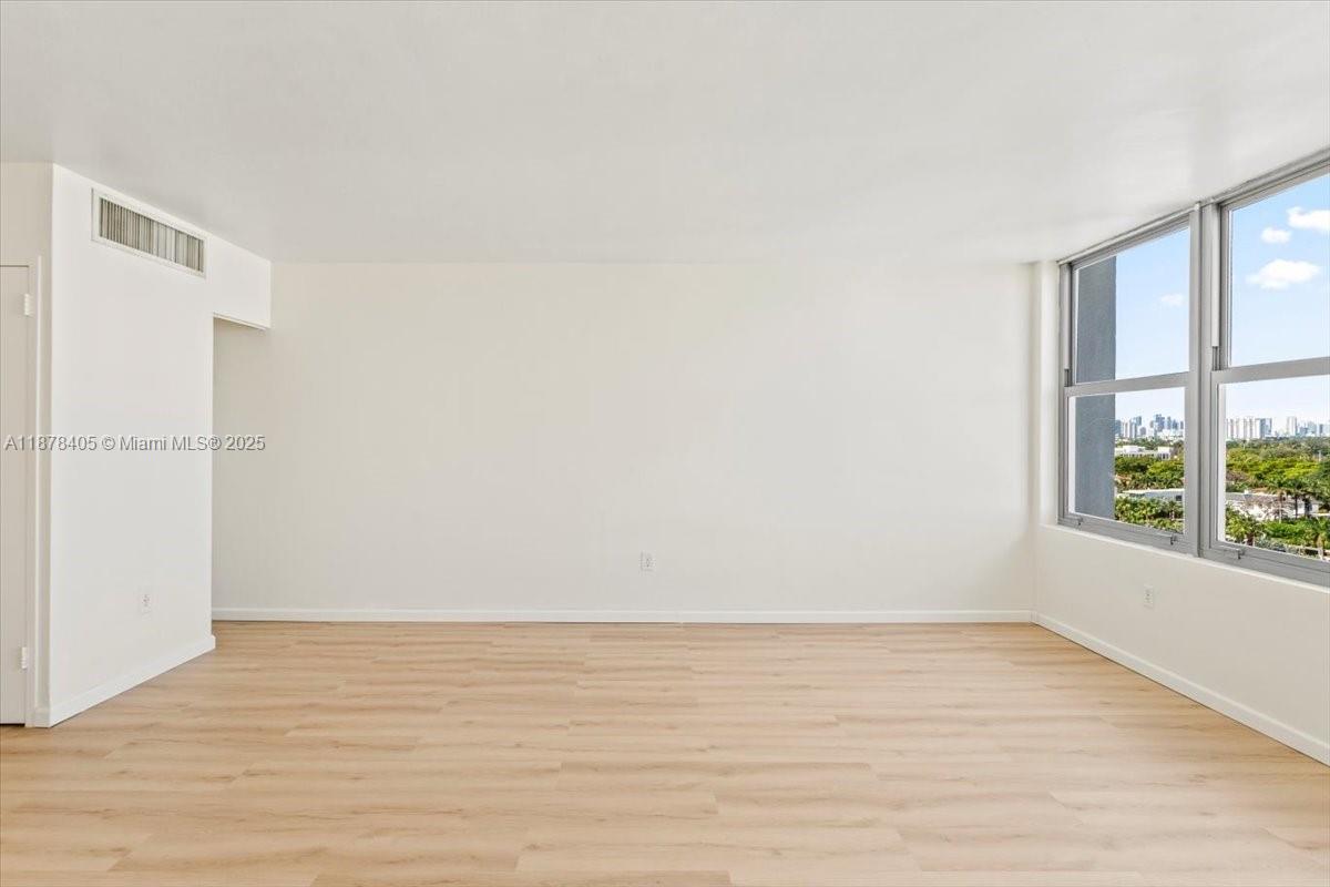 2899 Collins Avenue, Unit 1104 Miami Beach, FL 33140 - Photo 9 of 21 an empty room with wooden floor and windows