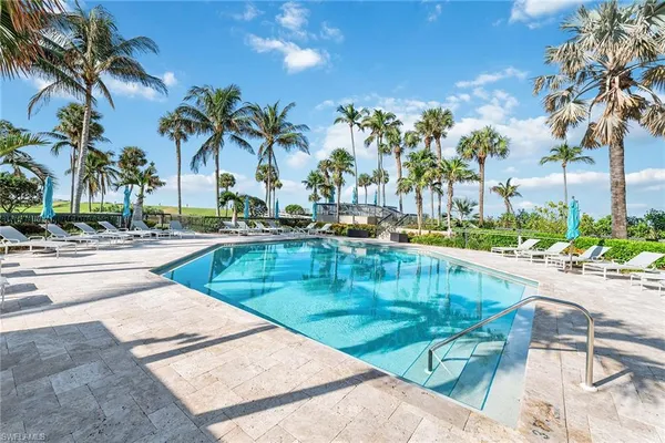 a view of swimming pool with outdoor seating and palm tree