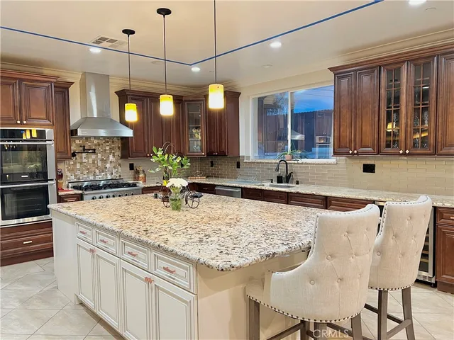 a kitchen with stainless steel appliances granite countertop a sink a stove and a wooden cabinets