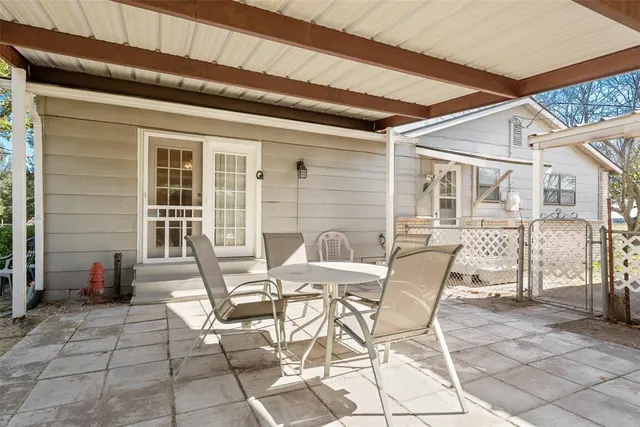a patio with table and chairs and potted plants