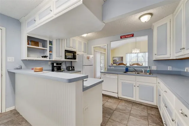 a kitchen with granite countertop white cabinets and white appliances