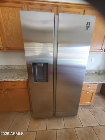 a view of a refrigerator in kitchen and an empty room