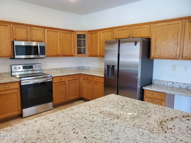 a kitchen with stainless steel appliances granite countertop a refrigerator a stove and a sink with cabinets
