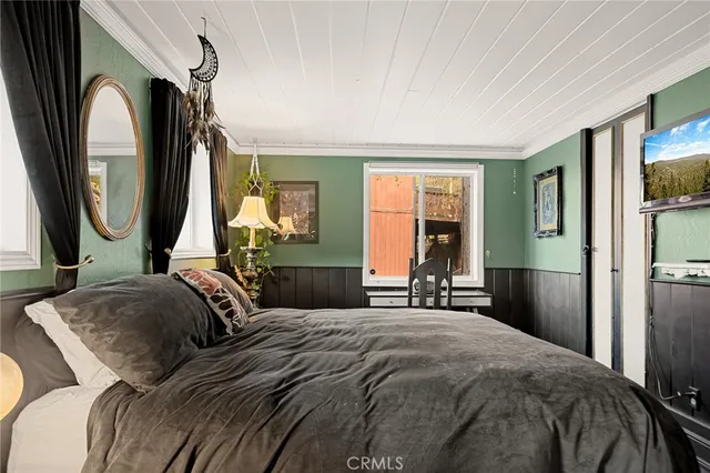 a bedroom with a bed a mirror and a large window