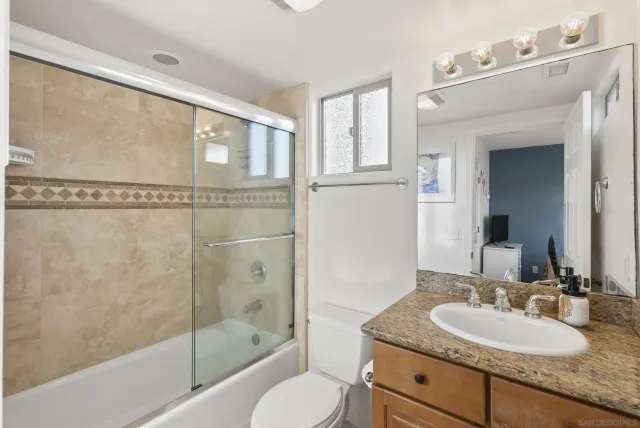 a bathroom with a granite countertop sink toilet and shower