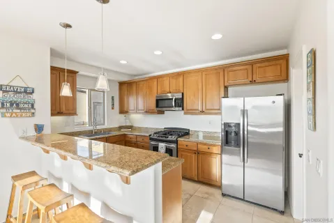 a kitchen with stainless steel appliances granite countertop a sink a stove a refrigerator a washer dryer and white cabinets