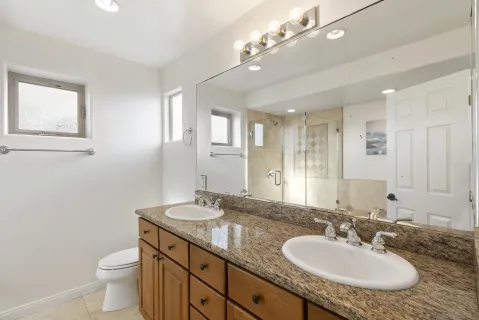 a bathroom with a granite countertop sink a toilet and a mirror